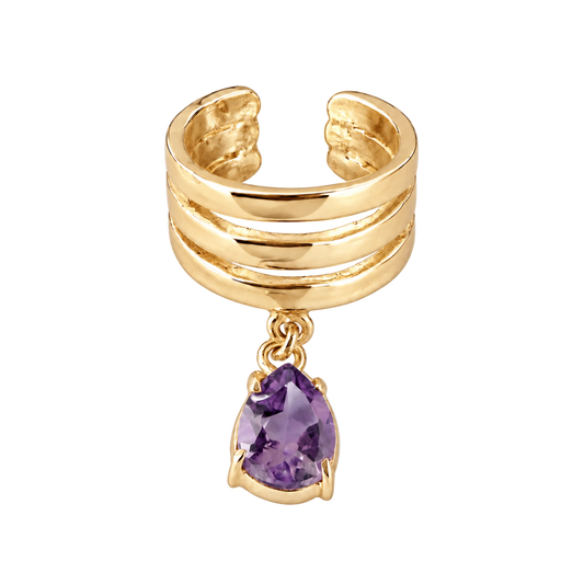 A gold-toned multi-band ring with a dangling teardrop-shaped purple gemstone, shown on a light gray background.