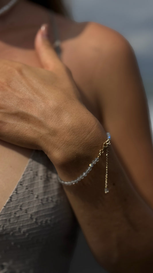A close-up of a delicate gold Sephina chain bracelet with faceted labradorite stones, featuring Sephina signature pendant.