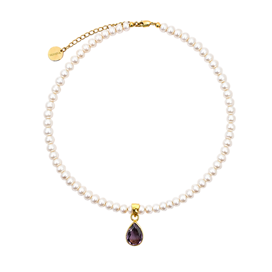 A Sephina freshwater pearl necklace with a gold chain extender and amethyst pendant.