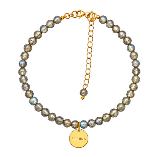A beaded bracelet made of metallic gray and labradorite  beads, featuring a gold chain extender, lobster clasp, and a 'SEPHINA' signature pendant.